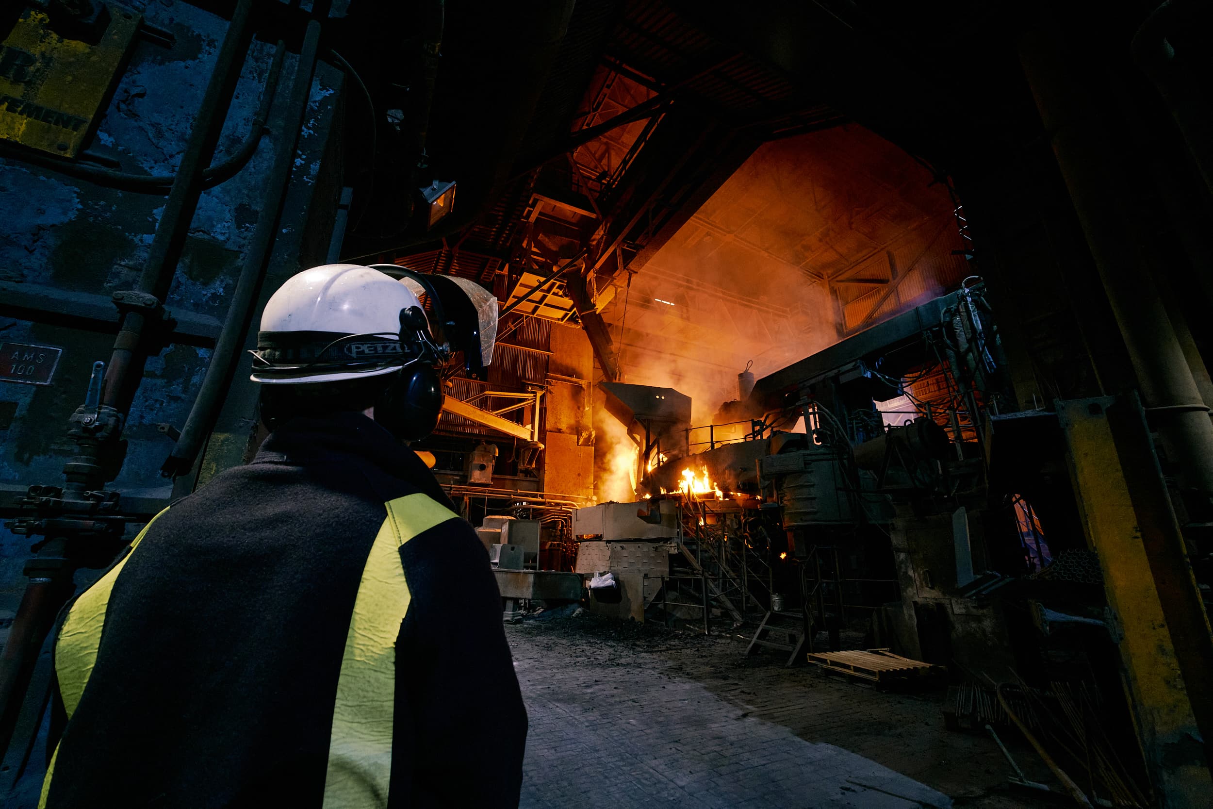 Worker in protective gear in a foundry with molten metal pour